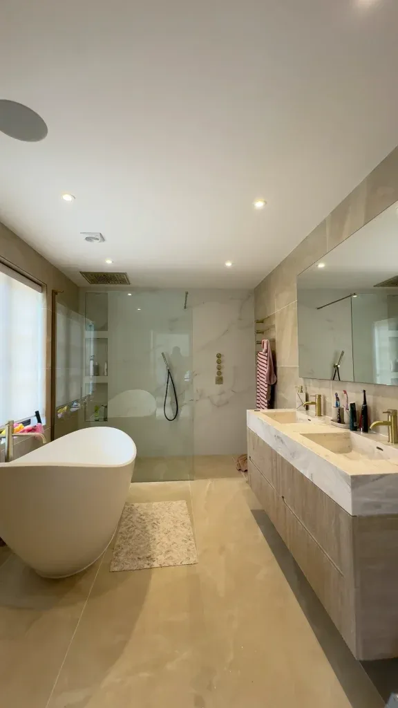 Renovated family bathroom in warm stone with freestanding bath and walk-in shower